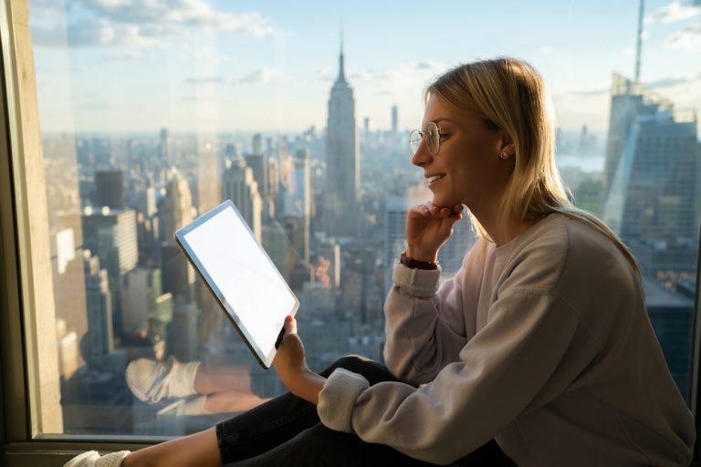 A digital nomad works in a comfortable hotel room overlooking the city in Thailand.