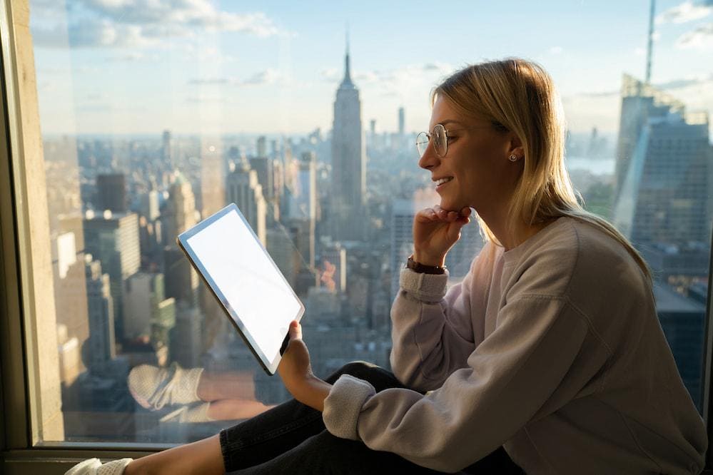 A digital nomad works in a comfortable hotel room overlooking the city in Thailand.