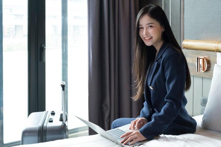 A businesswoman checks her laptop while staying in a room at a business travelers’ hotel.
