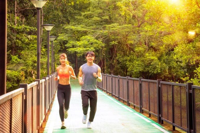 Runners on a tree-lined path during an early morning Sathorn city run in Bangkok.